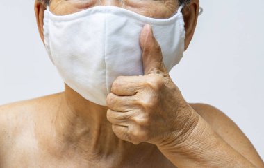 Kıdemli kadın el yapımı pamuklu bez maske, tıbbi maske, cerrahi maske, iç çekiş ile el beyaz, ön görüş, yakın çekim, covid19, Coronavirus, sağlık sigortası