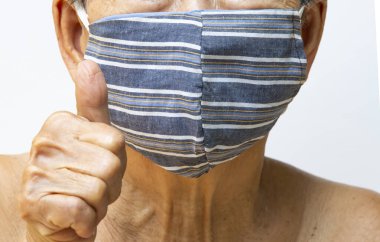 Kıdemli kadın el yapımı çizgili yüz maskesi, tıbbi maske, cerrahi maske, iç çekiş ile el beyaz, ön görüş, yakın çekim, covid19, Coronavirus, sağlık sigortası,