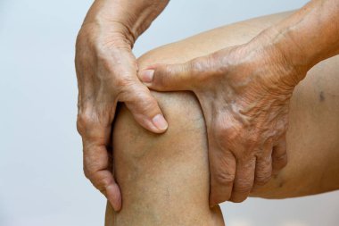 Sağ diz ağrısı çeken yaşlı bir kadın, beyaz arka planda elinin masajı, yakın çekim, Asyalı vücut parçası, sağlık sigortası, masaj konsepti...