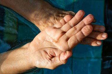 Kıdemli bir kadının elleri ellerini yıkaması, bokeh mavi havuz arka planında adım adım yıkaması, Makro sahneyi kapatması, seçici odak noktası, covid19, bakteri, sağlık konsepti, 7 adım el yıkama