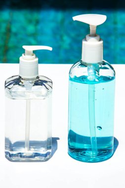 İnsanların elleri portatif el temizleyici jel pompası kullanıyor. Beyaz ve mavi üzerine alkol jeli dezenfektanı sürmüş. Yakın çekim, kovid19, Bakteri, Sağlık Hizmetleri, 7 adım el yıkama.