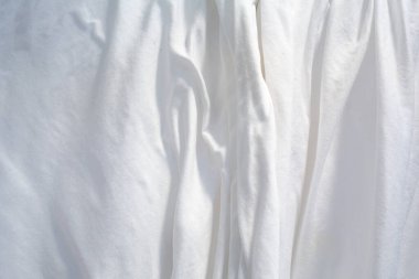 Güneşte kuruyan beyaz çarşaf, buruşuk doku, soyut arkaplan, yakın çekim, seçici odak, ev işi, çamaşır konsepti.