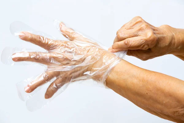 Руки Пожилой Женщины Одеты Одноразовую Защитную Пластиковую Перчатку Сером Фоне — стоковое фото