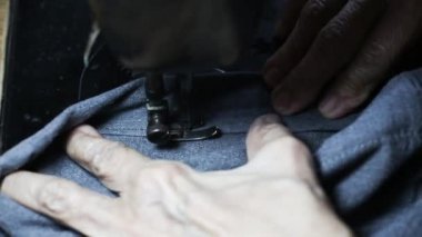 Yaşlı kadının dikiş makinesine diktiği gri kumaş, iplik, iğne, yakın çekim, seçici odak, dikiş süreci, kadın hobisi. Terzi konsepti