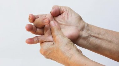 Orta parmağında tetik parmağı, sağ elinde masaj yapan yaşlı kadının sol eli beyaz arka planda ağrıdan muzdarip, yakın çekim, ofis sendromu, sağlık sigortası, masaj, Asyalı vücut konsepti.