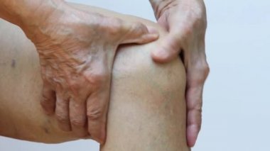 Sol diz ağrısından muzdarip son sınıf öğrencisi, beyaz arka planda elinin masajı, yakın çekim, Asyalı vücut parçası, sağlık sigortası, masaj konsepti...