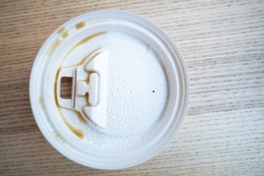 Tahta arka planda su damlaları olan bir kahve bardağının plastik kapağı, Üst Manzara, Yakın çekim, Seçici odak içki konsepti hakkında