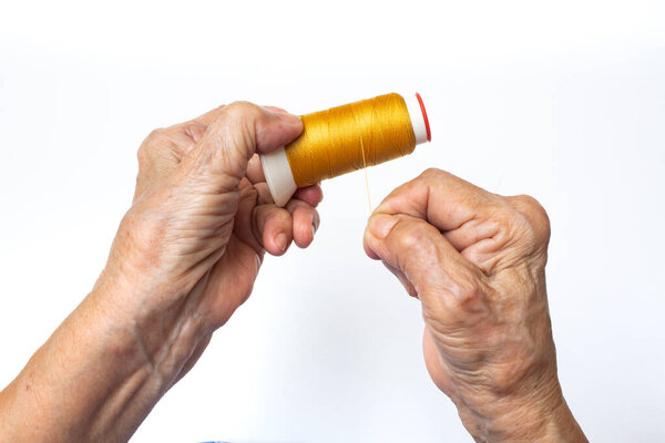 Senior woman hands spinning to yellow thread roll on isolated white background, Skeins of thread, Close up and macro shot Asian body part, Hobby, About Tailor Processing concept