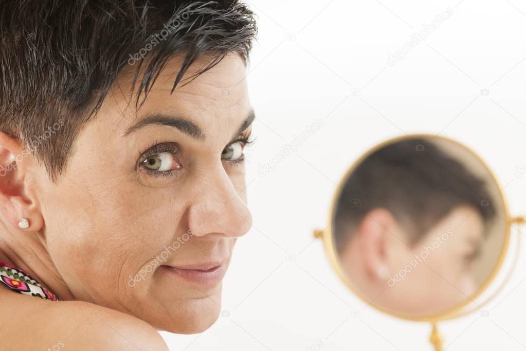 Face of woman looks into the camera with mirror