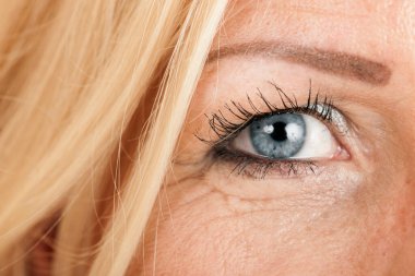 Close-up of the right eye of a blonde, blue-eyed middle-aged woman. clipart