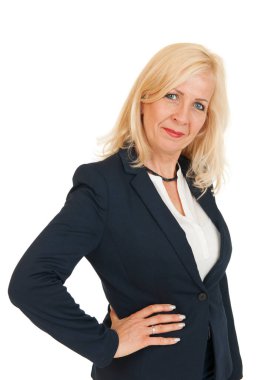 Sarışın, uzun saçlı, orta yaşlı bir kadının kalçasında sağ eli kalçasında, kameraya gülümseyen beyaz bir arka planda sırıtan bir kadının yan gövde portresi..