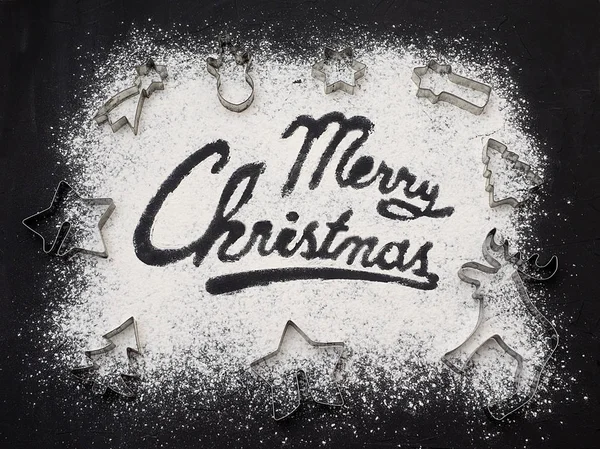 Merry Christmas word written black table. Christmas baking. Making gingerbread christmas cookies. Christmas concept. Top view. Copy space.