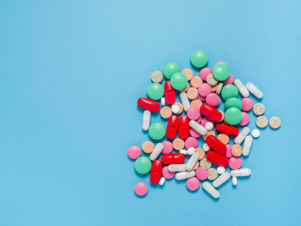 Цветные, зеленые, красные, белые таблетки на синем фоне, плоская кладка
