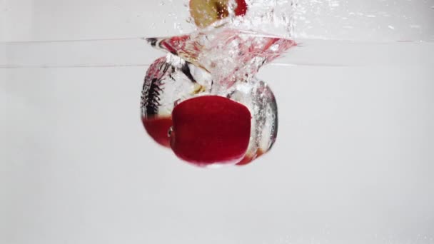 Яблоко падает в воду. — стоковое видео
