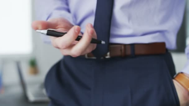 Un hombre de negocios mueve una pluma en varias direcciones . — Vídeos de Stock