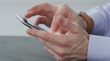 İşadamı bir cep telefonu kullanarak durur.