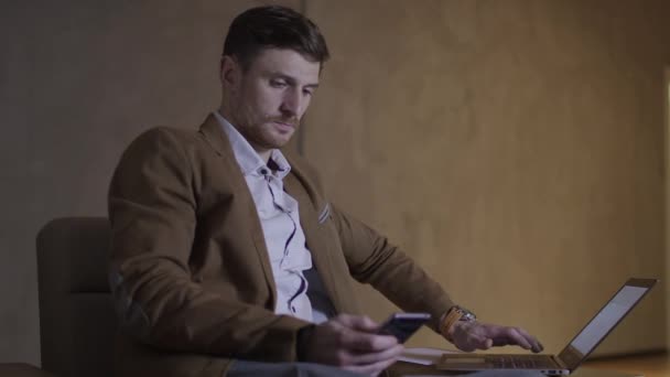 Homme d'affaires utilise à la fois son mobile nad un ordinateur portable . — Video