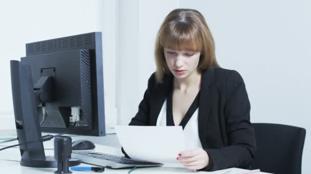Mujer bastante joven aburrida mientras lee un documento — Vídeos de Stock