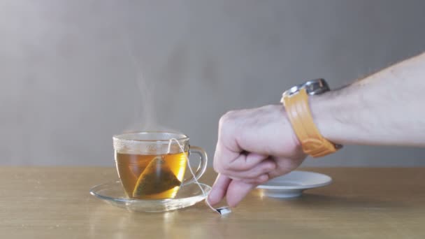 Homme sortant le sachet de thé d'une tasse 