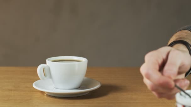 Человек кладет сахар в чашку кофе — стоковое видео