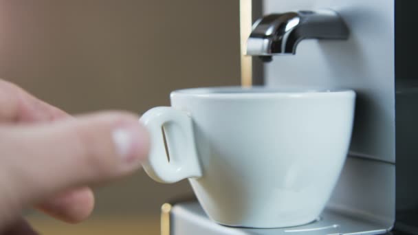 Junger Mann steckt eine Tasse in die Kaffeemaschine — Stockvideo