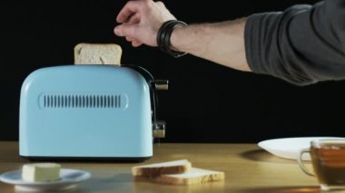 Adam iki tane ekmek bir elektrikli tost makinesi koyar.