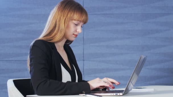 Mujer bastante joven sonriendo mientras usa una computadora — Vídeos de Stock