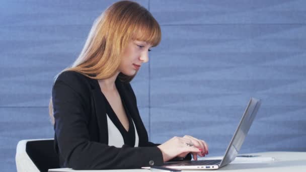 Mujer bastante joven sonriendo mientras usa una computadora — Vídeos de Stock