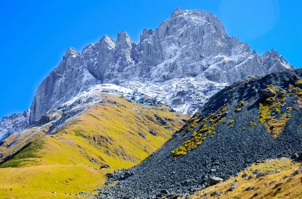Kaukasusberge im Sommer, grünes Gras, blauer Himmel und Schnee auf dem Gipfel tschukhebi. Dorf juta, Georgien — Stockfoto
