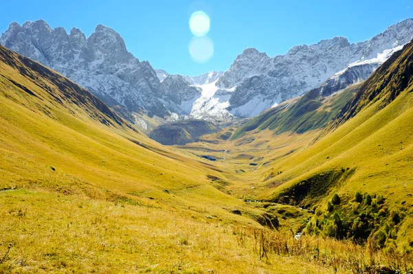 Cáucaso montanhas no verão, grama verde, céu azul e neve no pico Chiukhebi, aldeia Juta, Geórgia — Fotografia de Stock