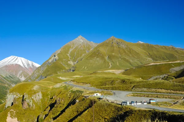 Montagne del Caucaso in estate, verdi colline, cielo azzurro e vetta innevata Mkinvari . — Foto Stock