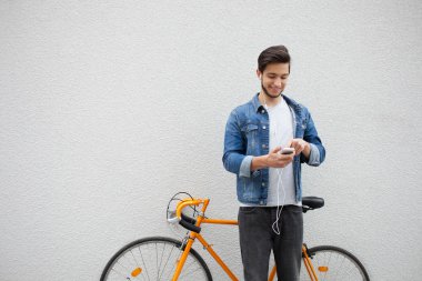Duvar da duran mavi kot ceketli adam. turuncu bisiklet yakın genç adam. Telefona bakan çanta ile gülümseyen öğrenci