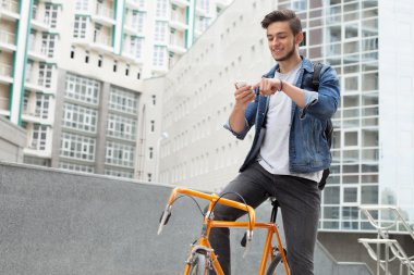 Mavi kot ceketli adam omzunda turuncu bisiklet taşıyor