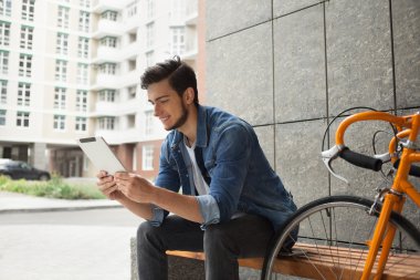 Denim ceket, tablet ve turuncu bisiklet Guy