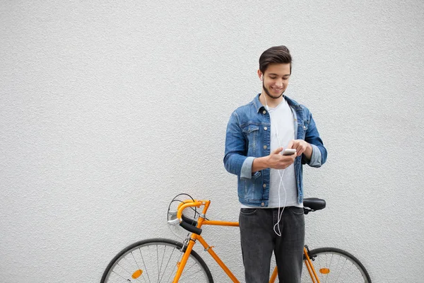 Duvar da duran mavi kot ceketli adam. turuncu bisiklet yakın genç adam. Telefona bakan çanta ile gülümseyen öğrenci