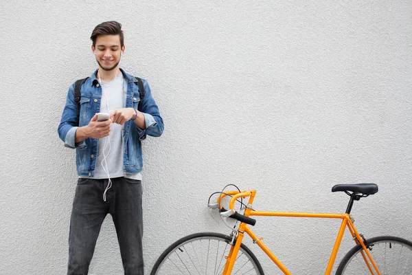 Duvar da duran mavi kot ceketli adam. turuncu bisiklet yakın genç adam. Telefona bakan çanta ile gülümseyen öğrenci