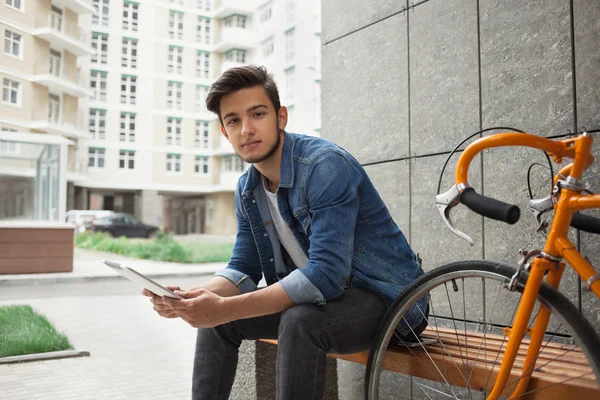 Denim ceket, tablet ve turuncu bisiklet Guy