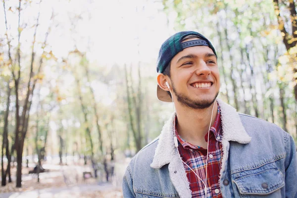 Uśmiechnięty człowiek słuchający muzyki w jesiennym parku — Zdjęcie stockowe