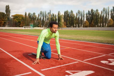 Sportif delikanlı koşu parkurundakilerden çalışmaya hazır. Büyük güzel modern Stadı nda düzgün biçimli insanların uygun