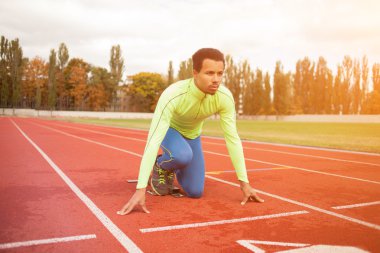 Sportif delikanlı koşu parkurundakilerden çalışmaya hazır. Büyük güzel modern Stadı nda düzgün biçimli insanların uygun