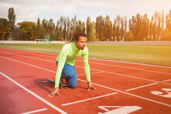 Junge sportliche Mann sind bereit, auf der Rennstrecke zu laufen. fit gut ausgebildete Menschen in großen schönen modernen Stadion — Stockfoto