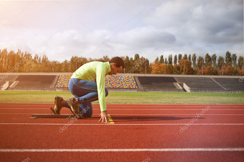 Young sporty man are ready to run on racetrack. at large nice modern stadium