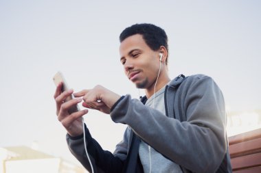 adam spor üniforma ve kulaklıklar bir smartphone kullanarak müzik dinleme