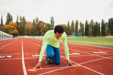 Sportif delikanlı koşu parkurundakilerden çalışmaya hazır. Büyük güzel modern Stadı nda düzgün biçimli insanların uygun