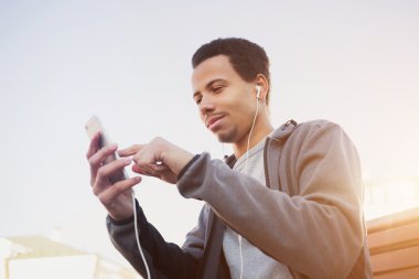 adam spor üniforma ve kulaklıklar bir smartphone kullanarak müzik dinleme