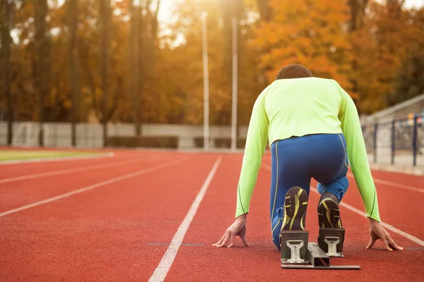 Young sporty man are ready to run on racetrack. Fit well formed people at large nice modern stadium