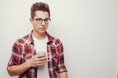 ciddi yüz beyaz fincan çay veya kahve içme tutan gömlekli şık saç modeli ile yakışıklı adam