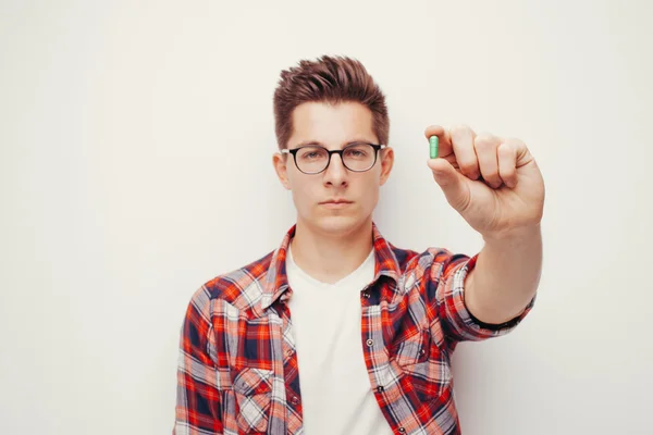 Jovens homens sérios em camisa vermelha segurando alguma mão pílula — Fotografia de Stock