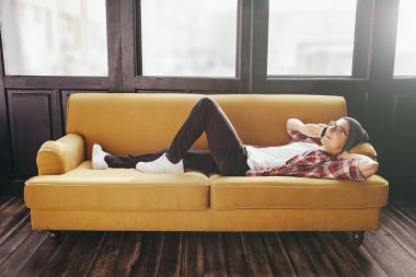 kanepede rahatlatıcı ve onun akıllı telefonu konuşurken genç adam