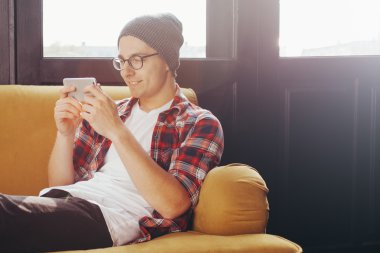 kanepede rahatlatıcı ve onun akıllı telefon arayan genç adam